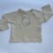 Maglia beige a maniche lunghe per bambini con bottoni in legno sulla spalla e grafica, perfetta per un look comodo ed elegante.