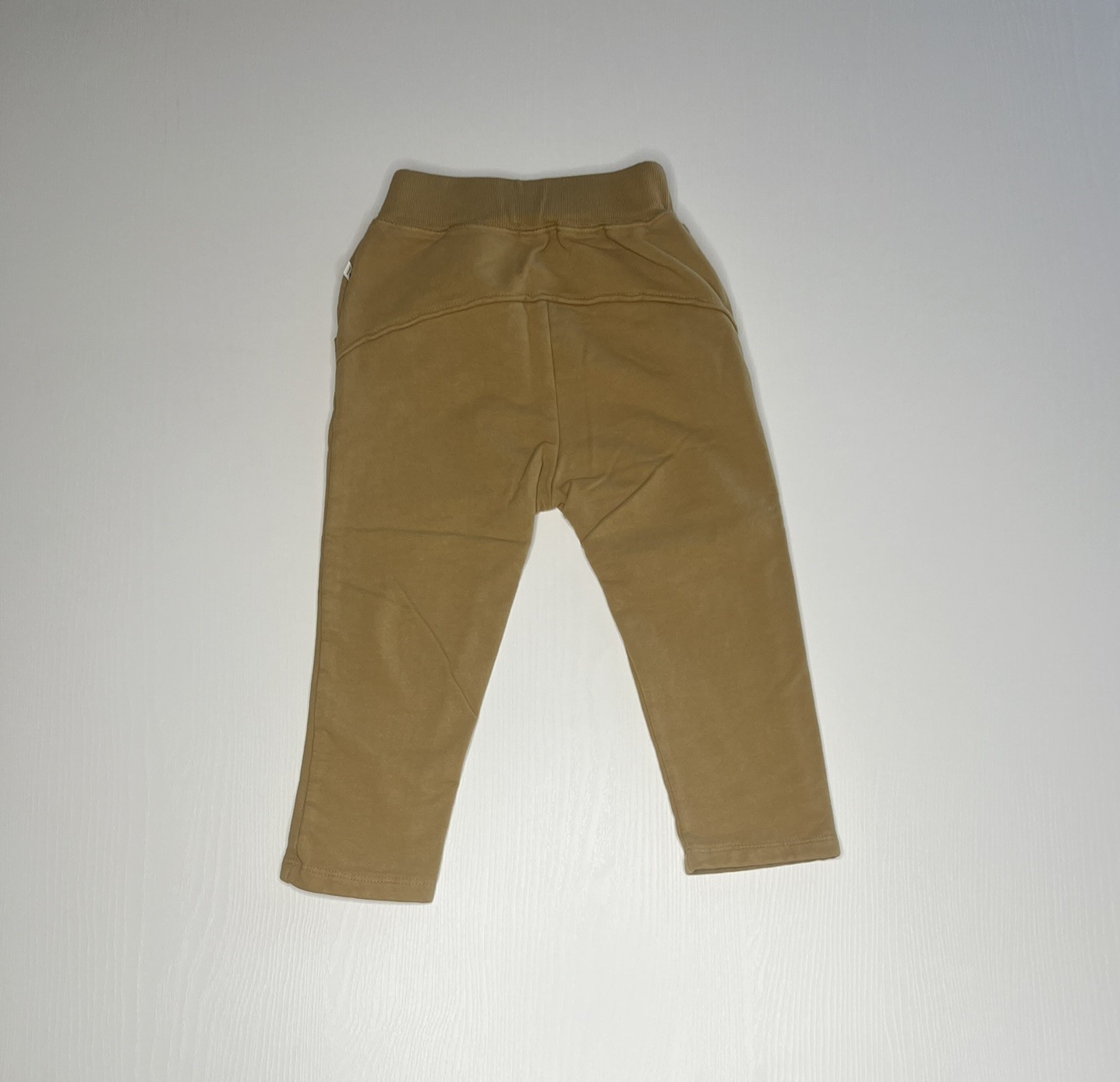 Pantaloni ocra per bambini con elastico in vita, laccetto decorativo e tasche laterali, comodi e pratici per ogni occasione.