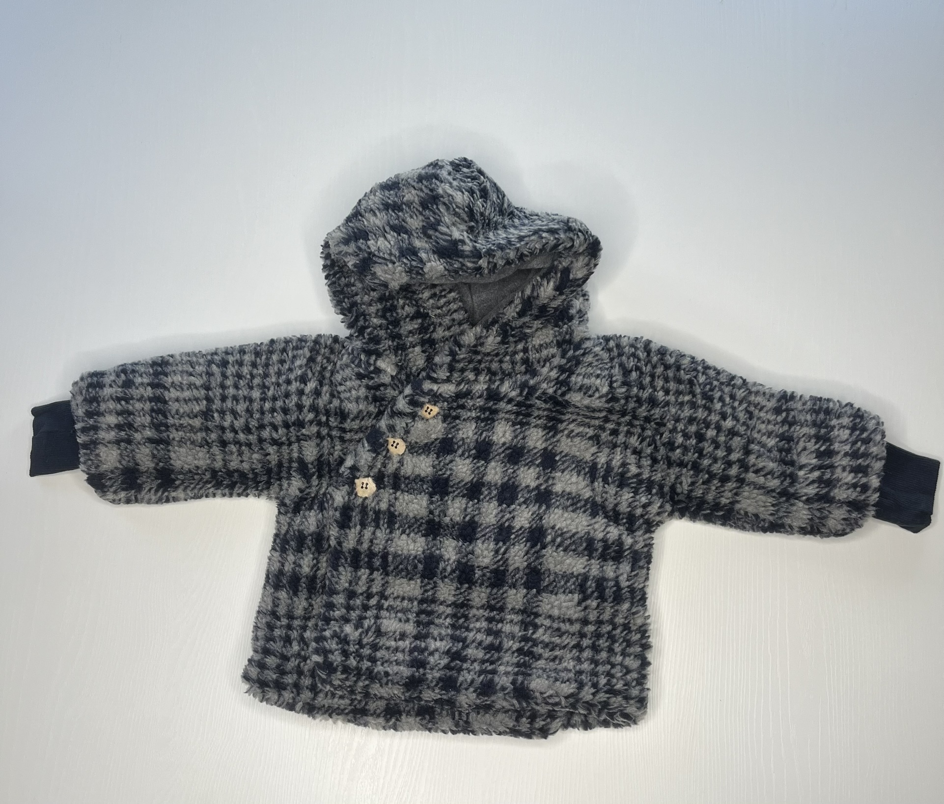 Morbido cappotto in pile a quadri blu e bianchi per neonati, con cappuccio e piedini integrati.